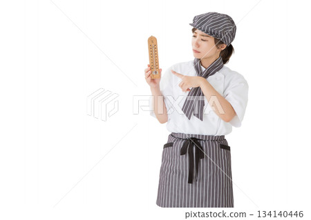 A woman wearing a chef's coat holding a thermometer A woman wearing a chef's coat holding a thermometer 134140446
