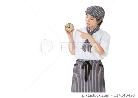 一位身穿廚師服的女子拿著一個鐘錶 一位身穿廚師服的女子拿著一個鐘錶 134140456