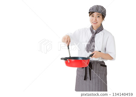 A woman wearing a chef's coat holding a frying pan 134140459