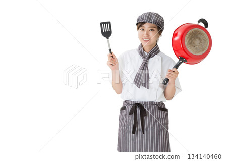 A woman wearing a chef's coat holding a frying pan A woman wearing a chef's coat holding a frying pan 134140460