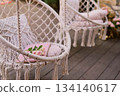 The swing is light wicker with a soft pillow in the style of macrome. Boho style, garden design. 134140617