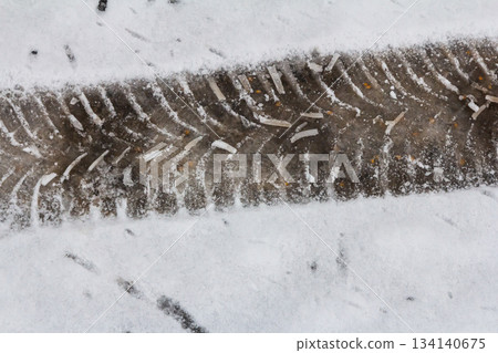 Tire tracks on a snowy ground showing the contrast between frozen landscape and dirt below Tire tracks on a snowy ground showing the contrast between frozen landscape and dirt below 134140675