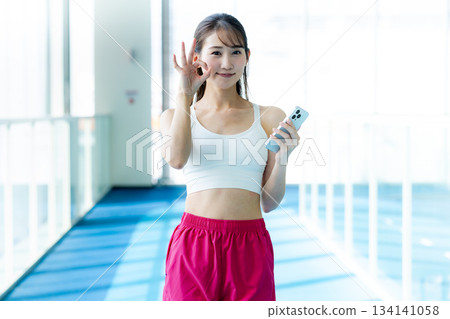 Woman with smartphone at the gym 134141058