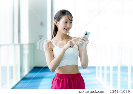 在健身房用智慧型手機的女人 在健身房用智慧型手機的女人 134141059