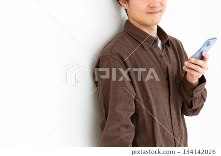 一位身著休閒裝的中年男子麵帶微笑,手裡拿著一部智慧型手機 一位身著休閒裝的中年男子麵帶微笑,手裡拿著一部智慧型手機 134142026