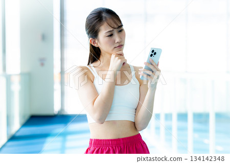 Woman using smartphone at the gym 134142348