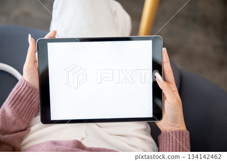 Close up woman student holding tablet with both hands reading or watching video as sitting in cafe. Close up woman student holding tablet with both hands reading or watching video as sitting in cafe. 134142462