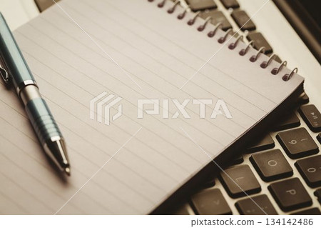 Spiral-bound notebook and ballpoint pen are resting on laptop keyboard in 3D render 134142486