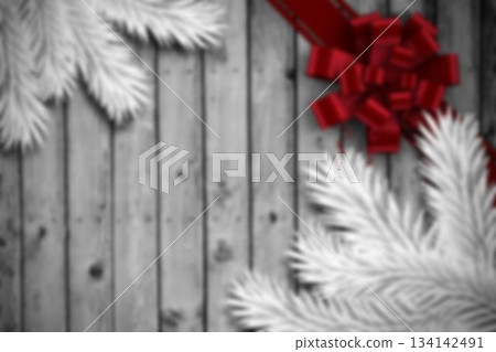 Red ribbon bow is shining on rustic wooden plank surface with white pine branches, copy space 134142491