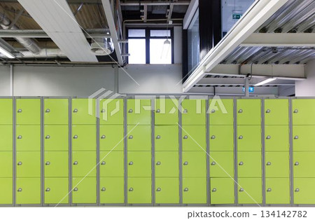 Lockers are standing in flat design against white wall under exposed ducts, steel beams, copy space Lockers are standing in flat design against white wall under exposed ducts, steel beams, copy space 134142782