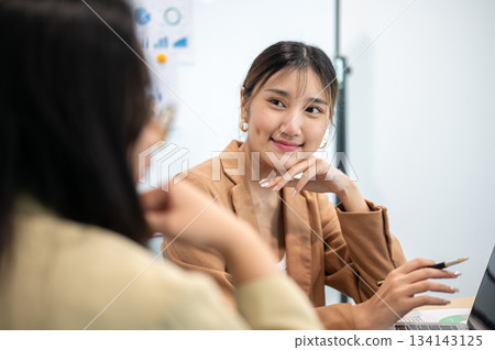 Asian businesswoman office worker holding a pen under chain looking at laptop on table in white room Asian businesswoman office worker holding a pen under chain looking at laptop on table in white room 134143125