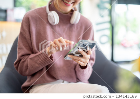 Asian businesswoman office worker holding a pen under chain looking at laptop on table in white room 134143169