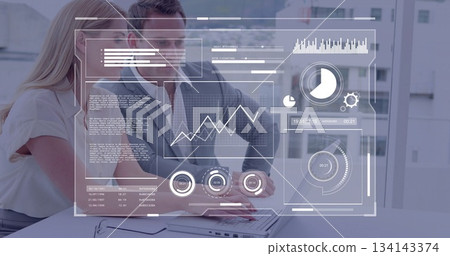 Colleagues in business attire analyzing data and typing on laptop in office, with HUD display Colleagues in business attire analyzing data and typing on laptop in office, with HUD display 134143374