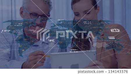 Collaborating business professionals analyzing data on tablet in office with world map overlay 134143376