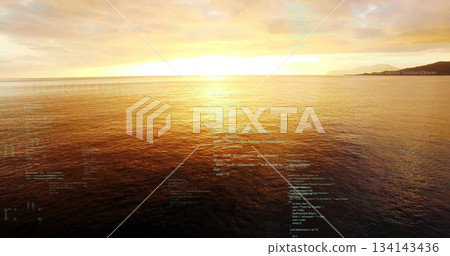 Glowing sun scattering golden reflection on ocean surface at dusk, with clouds and far coastline Glowing sun scattering golden reflection on ocean surface at dusk, with clouds and far coastline 134143436