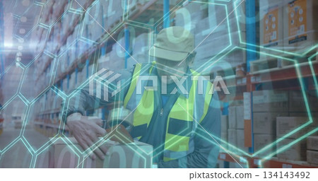 Warehouse worker wearing safety vest sealing boxes with tape dispenser in aisle, with data overlay 134143492
