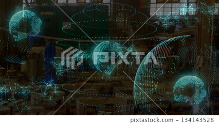 Standing technicians in blue uniforms inspecting machines on shop floor, with holographic network 134143528