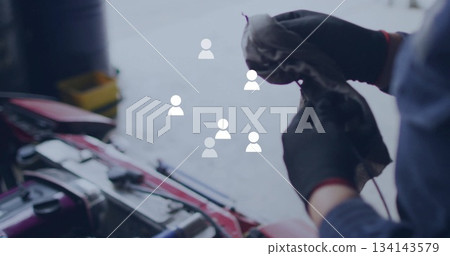Cleaning mechanic wiping engine in garage, with rag by red car hood, tool bin, copy space Cleaning mechanic wiping engine in garage, with rag by red car hood, tool bin, copy space 134143579