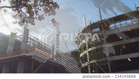 Rising concrete frame at urban site, with scaffolding, cranes, tree branch and map overlay 134143688