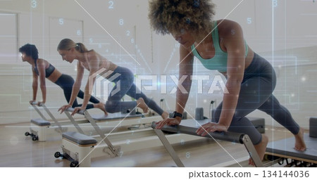 Balancing woman wearing green sports bra lunging on reformer machine in pilates studio, copy space Balancing woman wearing green sports bra lunging on reformer machine in pilates studio, copy space 134144036