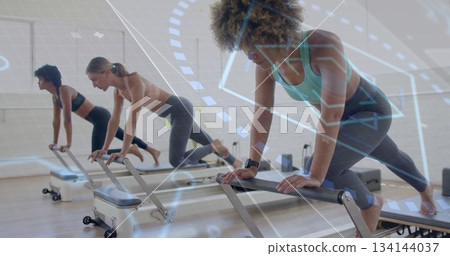 Woman in teal sportswear practicing Pilates on reformers in Pilates studio, with digital overlays Woman in teal sportswear practicing Pilates on reformers in Pilates studio, with digital overlays 134144037
