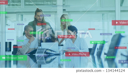 Collaborating five professionals showing software features in glass office, with laptops and tablet 134144124