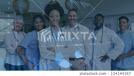 Standing medical team smiling in hospital corridor, with stethoscopes, scrubs and lab coats 134144167