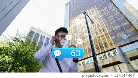 Standing man wearing white shirt speaking into smartphone on street, with coffee cup, chat bubble 134144407