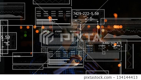 Man wearing dark checkered shirt reviewing data panels at dark workspace, with smartphone in hand Man wearing dark checkered shirt reviewing data panels at dark workspace, with smartphone in hand 134144413