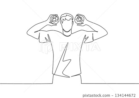 One line drawing of a young man playfully holding two donuts, reflecting fun and joy. Food concept with a festive international theme, National Donut Day. 134144672