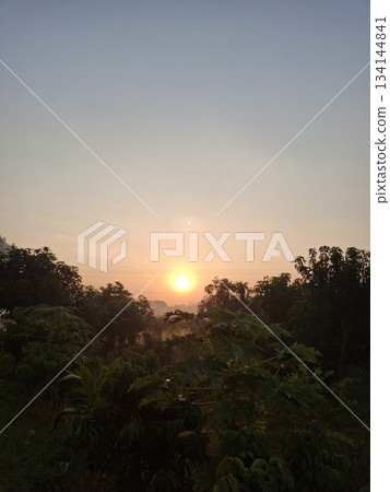 A breathtaking sunset casts a warm golden glow over a landscape of rolling green hills and dense trees A breathtaking sunset casts a warm golden glow over a landscape of rolling green hills and dense trees 134144841