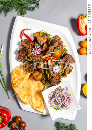 Top view of braised ribs with flatbread and onions on grey background. Top view of braised ribs with flatbread and onions on grey background. 134145329