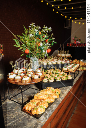 Elegant buffet table with canapes and pastries at event 134145334