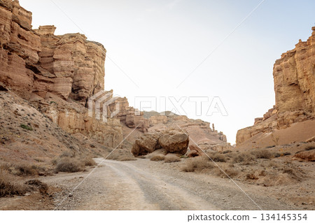 Wide shot of canyon with dusty road between rocky walls - wild nature landscape. Wide shot of canyon with dusty road between rocky walls - wild nature landscape. 134145354