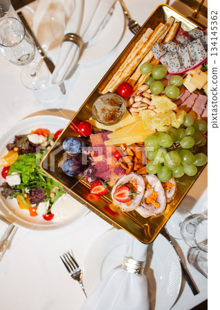 Top view of golden tray with cheese, fruit and appetizer assortment - luxurious buffet 134145362