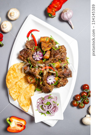 Top view of braised ribs with potatoes and onions on grey background - appetizing dish Top view of braised ribs with potatoes and onions on grey background - appetizing dish 134145389