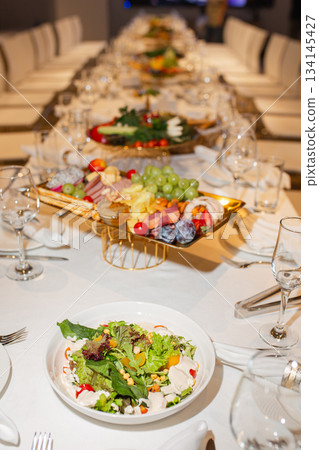 Wide shot of long set table with appetizer and salad assortment - elegant buffet Wide shot of long set table with appetizer and salad assortment - elegant buffet 134145427