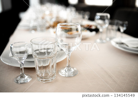 Restaurant. A table set for dinner. Cutlery, glasses and napkins on a table covered with a white tablecloth Restaurant. A table set for dinner. Cutlery, glasses and napkins on a table covered with a white tablecloth 134145549