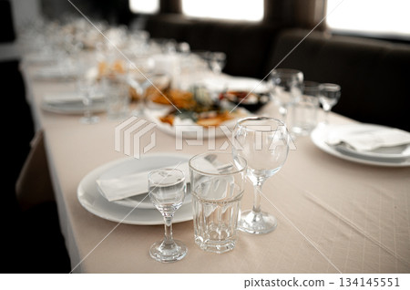 Restaurant. A table set for dinner. Cutlery, glasses and napkins on a table covered with a white tablecloth Restaurant. A table set for dinner. Cutlery, glasses and napkins on a table covered with a white tablecloth 134145551