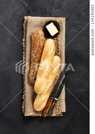 Assorted Baguettes on Burlap with Rustic Knife and Dark Background Assorted Baguettes on Burlap with Rustic Knife and Dark Background 134145803
