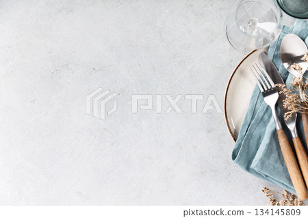 Rustic Table Setting with Blue Linen and Wooden Cutlery on Light Background Rustic Table Setting with Blue Linen and Wooden Cutlery on Light Background 134145809