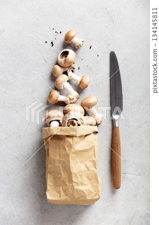 Fresh Brown Mushrooms in a Paper Bag on Light Stone Background 134145811