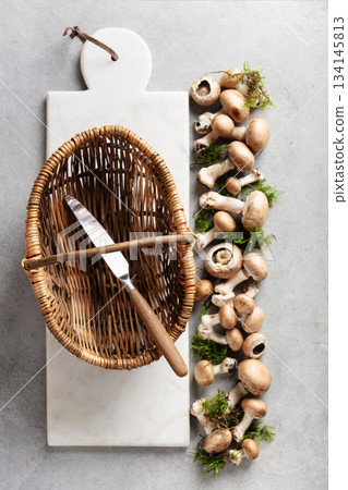 Wicker Basket and Fresh Mushrooms on Marble Cutting Board 134145813