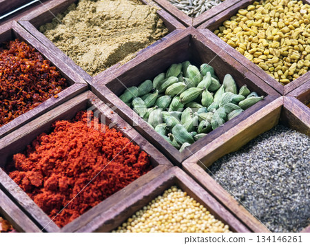 Colorful spices arranged in wooden boxes at a market in the afternoon sun for cooking and flavoring meals 134146261