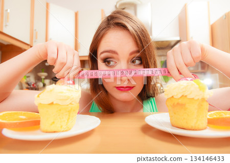 Woman with tape measure and cake. Diet dilemma. Woman with tape measure and cake. Diet dilemma. 134146433