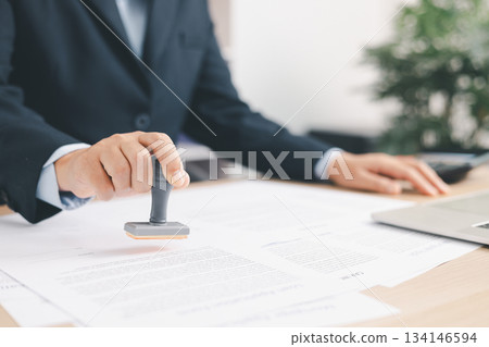 Businessman signing and stamping official document at desk, concept of legal contract approval, authorization or business agreement confirmation in corporate office background. stamp approval 134146594