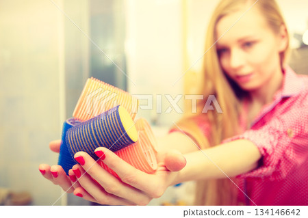 Happy woman holding hair rollers in bathroom Happy woman holding hair rollers in bathroom 134146642