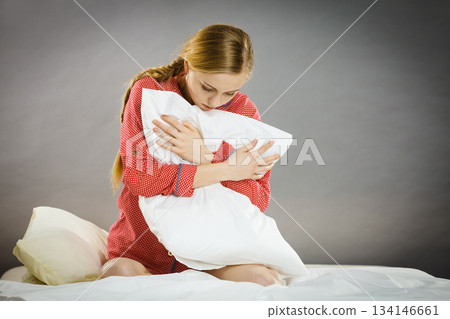 Sad depressed girl in bed gripping pillow 134146661