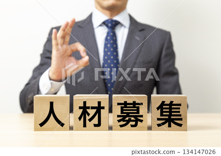 一位商人擺出「OK」的姿勢,旁邊立著一塊寫著「招募」的牌子。 一位商人擺出「OK」的姿勢,旁邊立著一塊寫著「招募」的牌子。 134147026