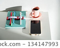 Notebook with pens, smartphone and cup on table. 134147993